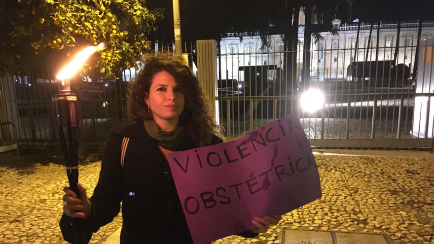 Una de las asistentes con antorcha y cartel frente al Parlamento andaluz.