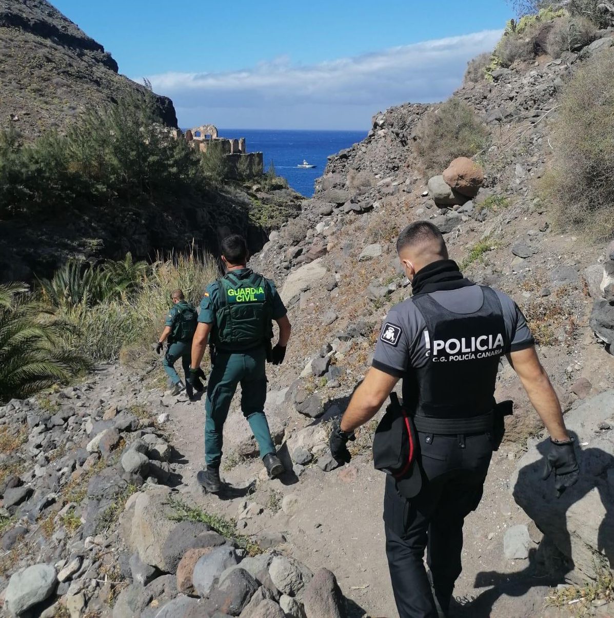 Agentes de la Guardia Civil y la Policía Canaria accediendo por un sendero a la playa de Guguy