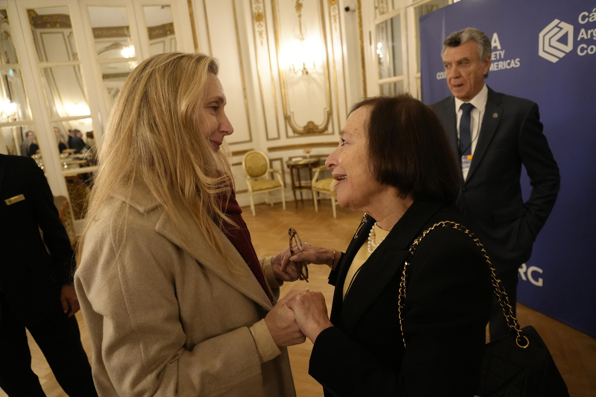 Karina Milei saluda a Susan Segal, presidenta del Council of the Americas. Detrás, Mario Grinman, de la Cámara de Comercio. El 20 de agosto de 2026, en el Hotel Alvear