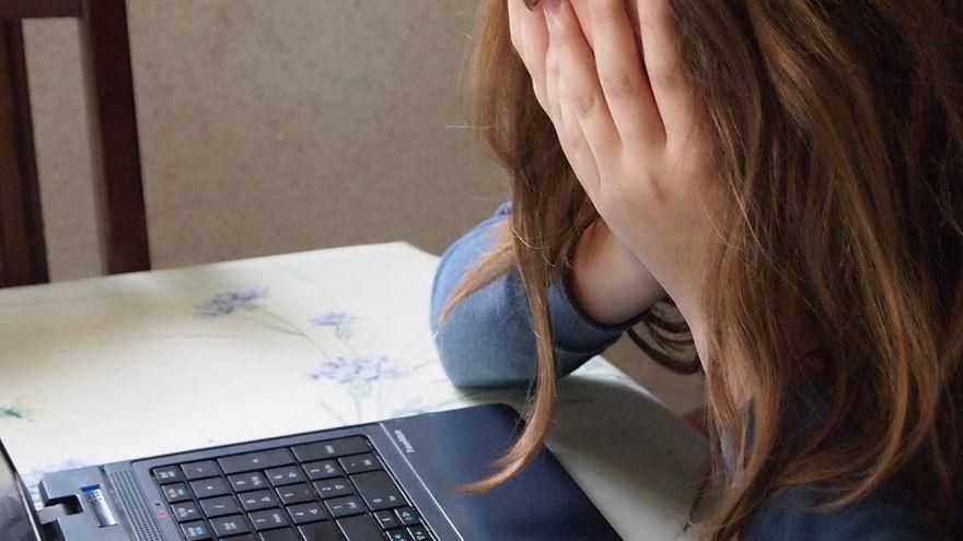 Fotografía de archivo de una menor tapándose la cara con ambas manos.