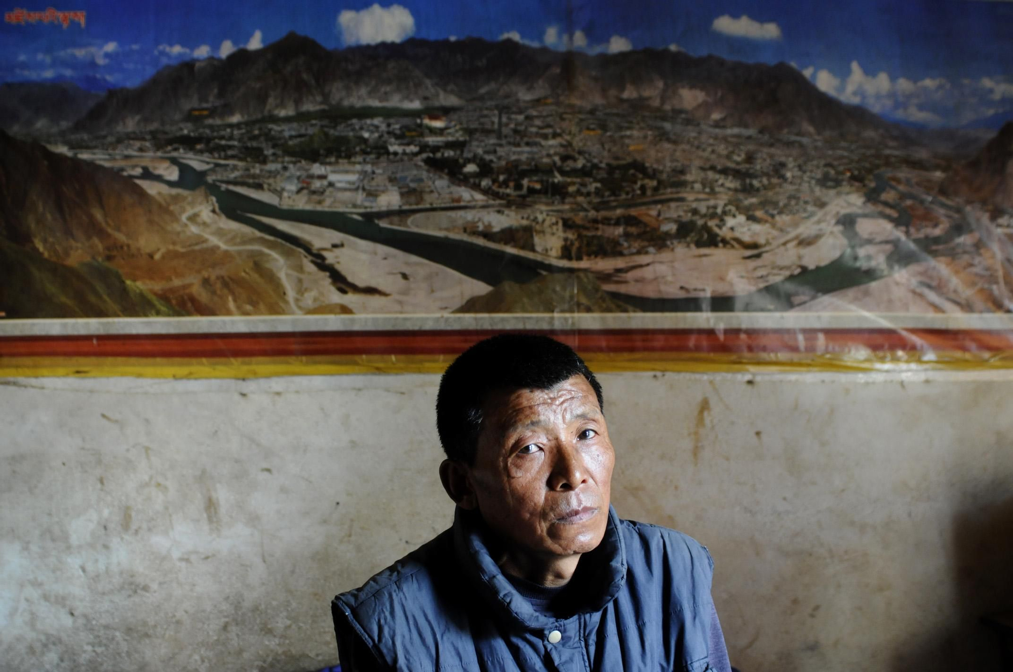 Jambu Sherpa trabajaba como guía en expediciones al Himalaya. Desde que se contagió con el VIH sabe que su sueño de visitar el Palacio de Potala, en Tíbet, no se hará realidad. Así que se conforma con verlo en el póster que cubre la sala de la infravivienda en la que vive junto a su mujer y sus dos hijos./ Zigor Aldama