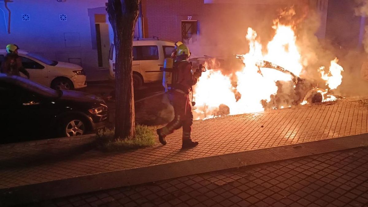 Dos bomberos, sofocando uno de los incendios en un coche.
