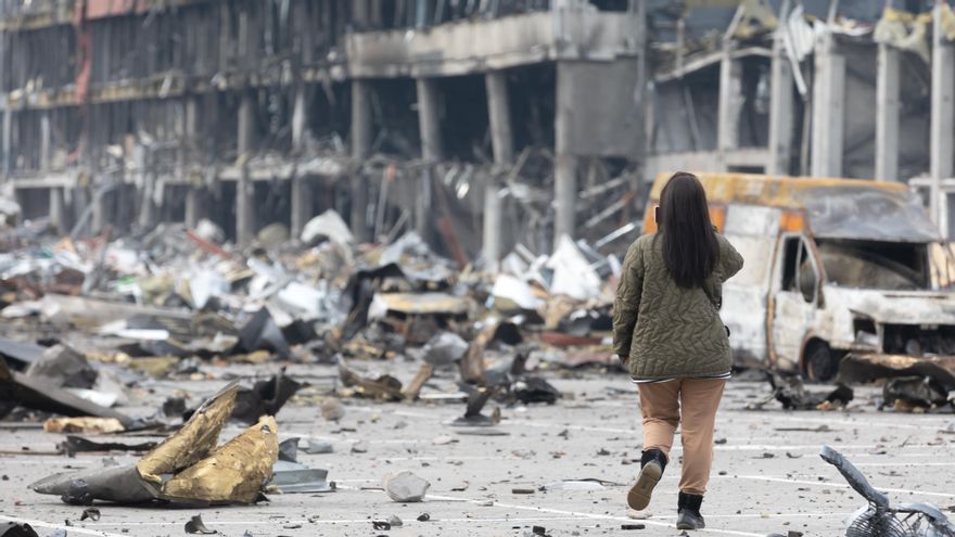 Una joven con un teléfono móvil toma fotos de un centro comercial de Retroville destruido tras un bombardeo ruso, Kiev, 29 de marzo.