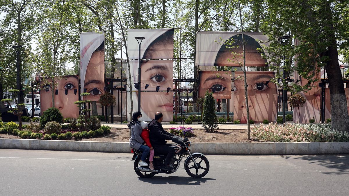 Ciudadanos iraníes pasan en coche junto a grandes retratos de las alumnas de la escuela Minab que murieron en un ataque aéreo en la plaza Tajrish de Teherán, el 21 de abril de 2026.