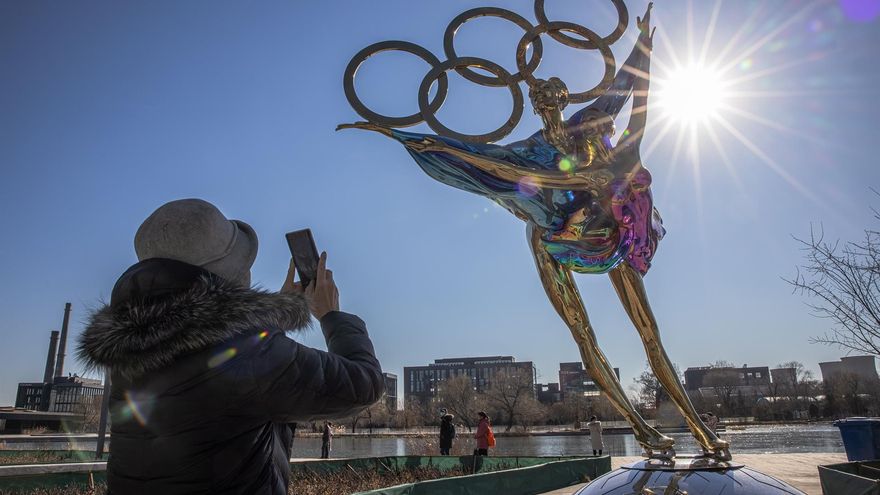 Una mujer fotografía una escultura de una pareja de patinaje artístico con motivo de los Juegos Olímpicos de Invierno 2022 en Pekín.