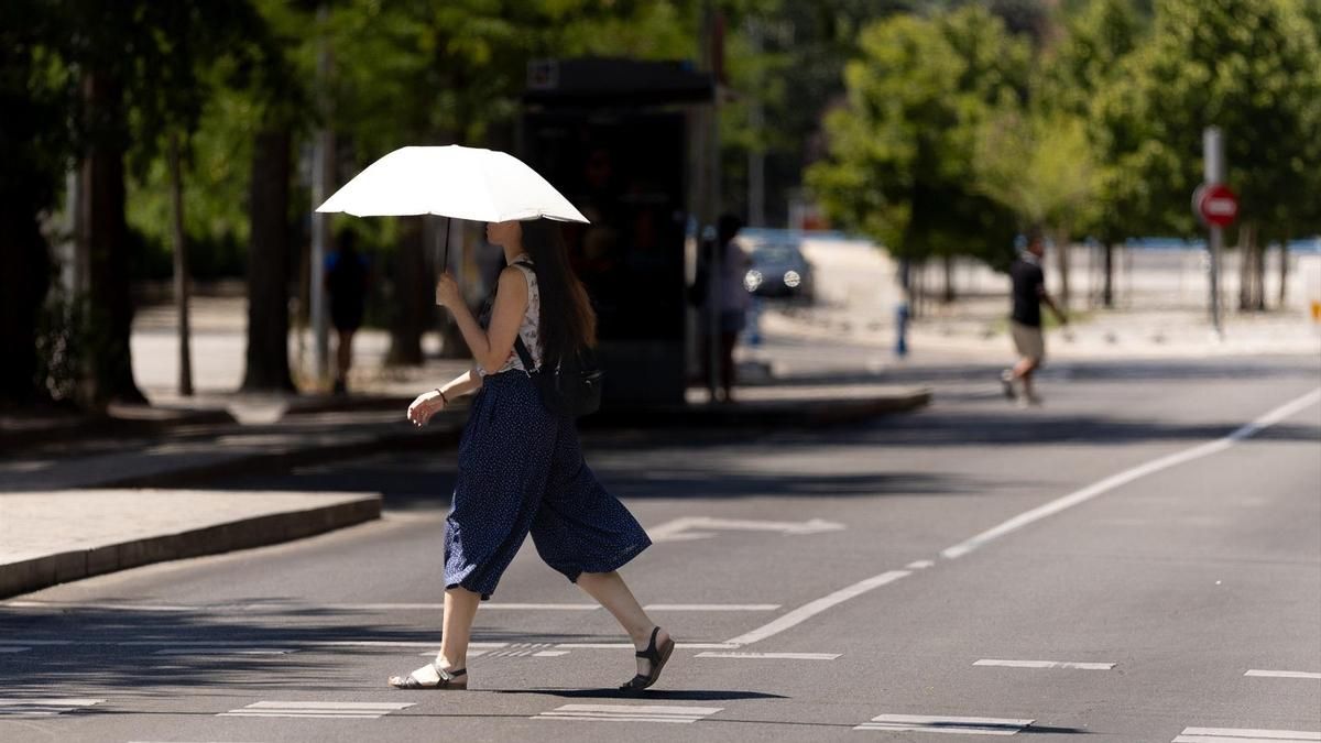 Una viandante se protege del calor con un paraguas por las calles de Madrid