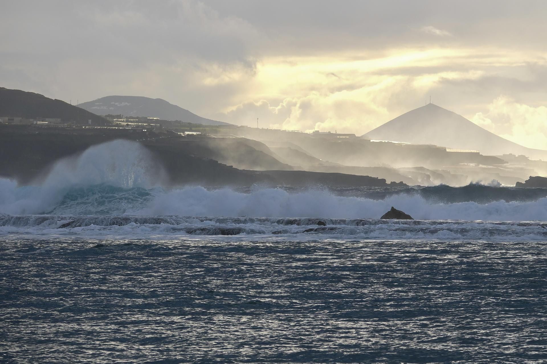 Oleaje este jueves por la tarde en la playa de Las Canteras, en Las Palmas de Gran Canaria, con los nubarrones de la borrasca Therese aproximándose ya desde Tenerife, tras la montañan de Gáldar, al fondo a la derecha. EFE/Angel Medina G.