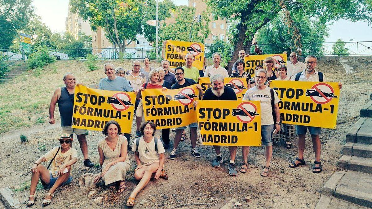 Varias personas posan junto a las obras para la F1 en IFEMA portando carteles contra el circuito