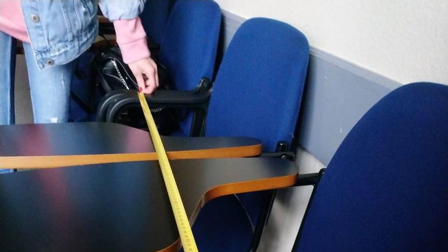 Una alumna mide la distancia entre asientos en una facultad de la ULPGC.