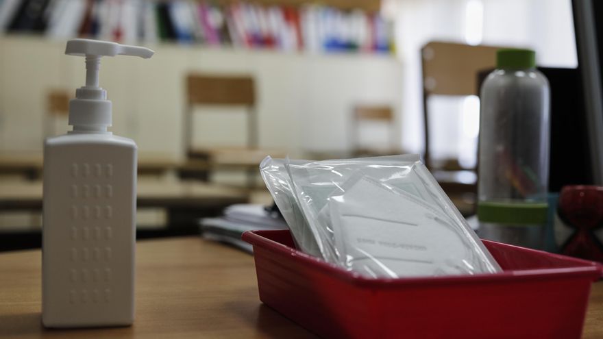 Mascarillas y gel desinfectante en la mesa del profesor de un aula