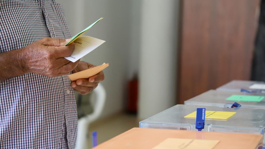 Un hombre sostiene sus papeletas de votación ante las urnas de la mesa en el colegio electoral. EFE / Luis G Morera