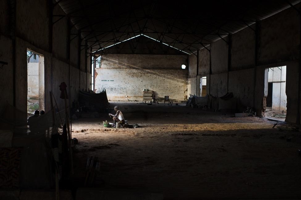 Ivone Pounendji, viuda y madre de siete hijos, de la aldea de Yamalé (PK30), camino de Bakala. Ella huyó al monte con sus hijos, entre los cuales su hija de 5 años está herida en un pie. "Pasamos dos años en el campo de desplazados internos de Notre Dame de la Victoire en Bambari y huimos por segunda vez en 2016. Hemos estado en esta antigua fábrica de algodón durante los últimos 18 meses". Ella sobrevive cocinando para los granjeros.