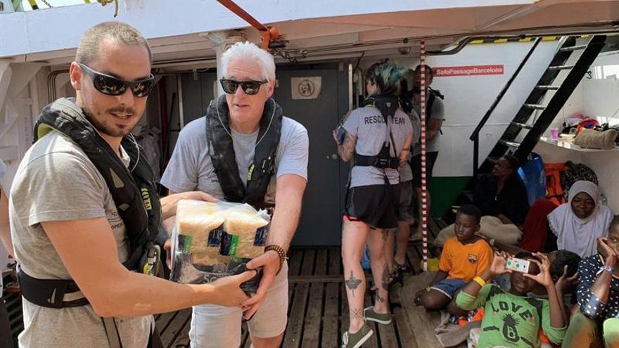 Fotografía facilitada por la ONG española Open Arms del actor estadounidense Richard Gere (c), que ha entregado víveres este viernes en el barco de la organización que acoge a 121 inmigrantes que esperan, a la altura de la isla italiana de Lampedusa, para pisar tierra firme desde hace una semana.