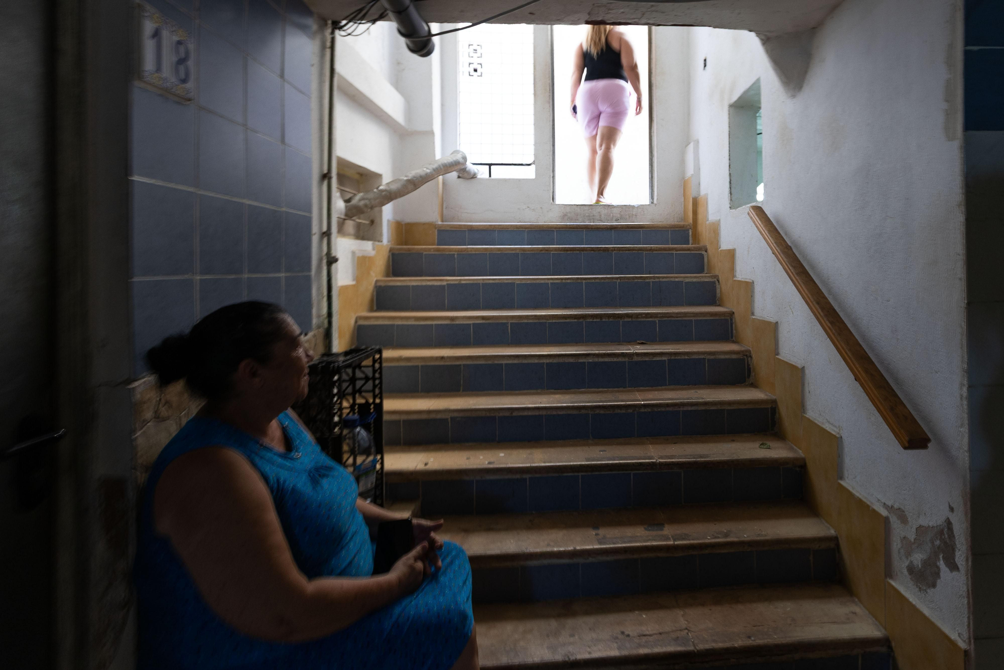 Reina, sentada, observa a otra de las inquilinas del sótano