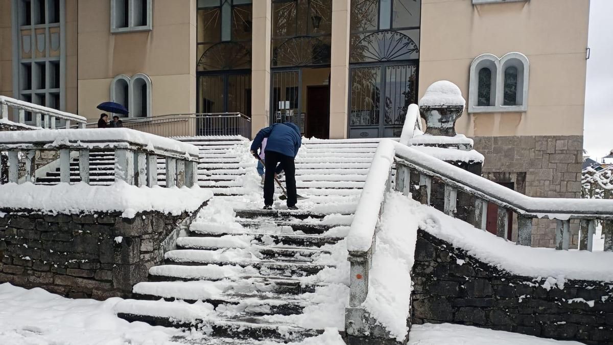 El cura de Villablino paleando la nieve de las escaleras de acceso a la iglesia de Santa Bárbara antes de la misa.