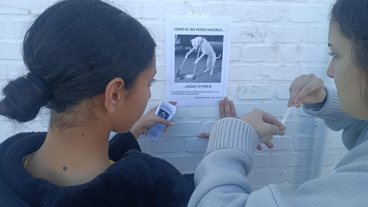 Los alumnos, instalando carteles para la recogida de excrementos.