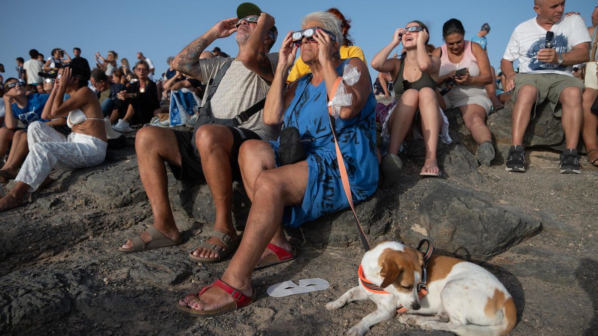 Varias personas contemplan desde la localidad de El Cotillo, en la isla de Fuerteventura, el eclipse solar de este miércoles.