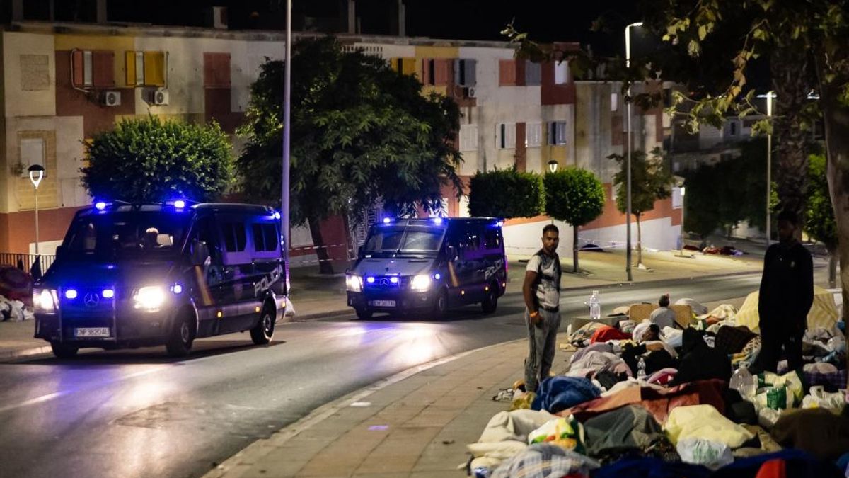 Los vehículos policiales llegan al asentamiento en las calles de Loma Colmenar para iniciar el traslado a un nuevo campamento oficial, mientras aún siguen durmiendo cientos de migrantes