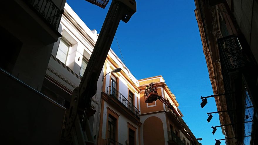 Varios operarios realizan mediciones en la calle Sierpes con vistas a la colocación de los nuevos toldos.