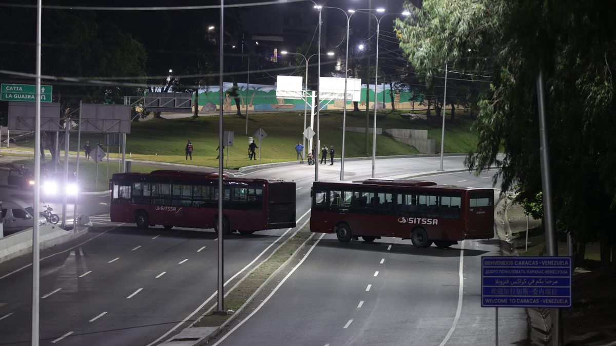 Dos autobuses bloquean una de las carreteras de acceso a Caracas, Venezuela este sábado tras haberse registrado varias detonaciones