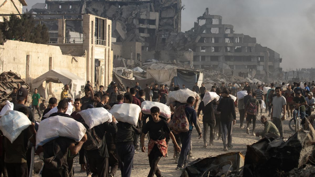 Desplazados palestinos llevan paquetes de ayuda humanitaria a lo largo de la calle Rashid, al oeste de Yabalia, el 22 de junio .
