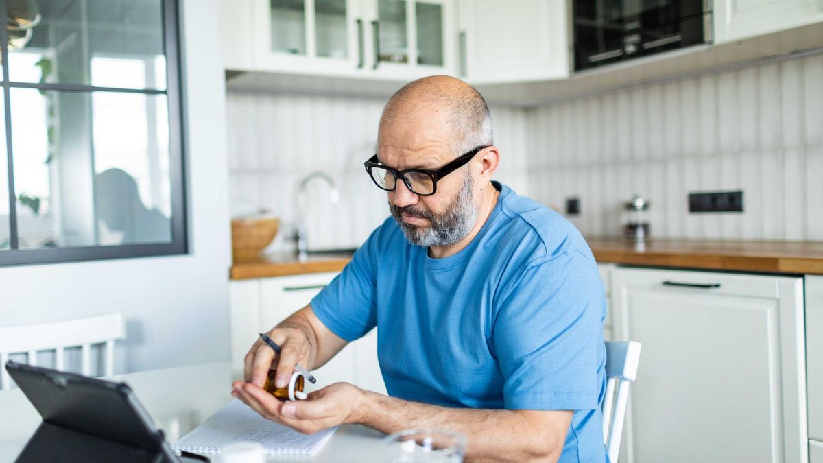 Un hombre toma una medicina mientras habla con su médico