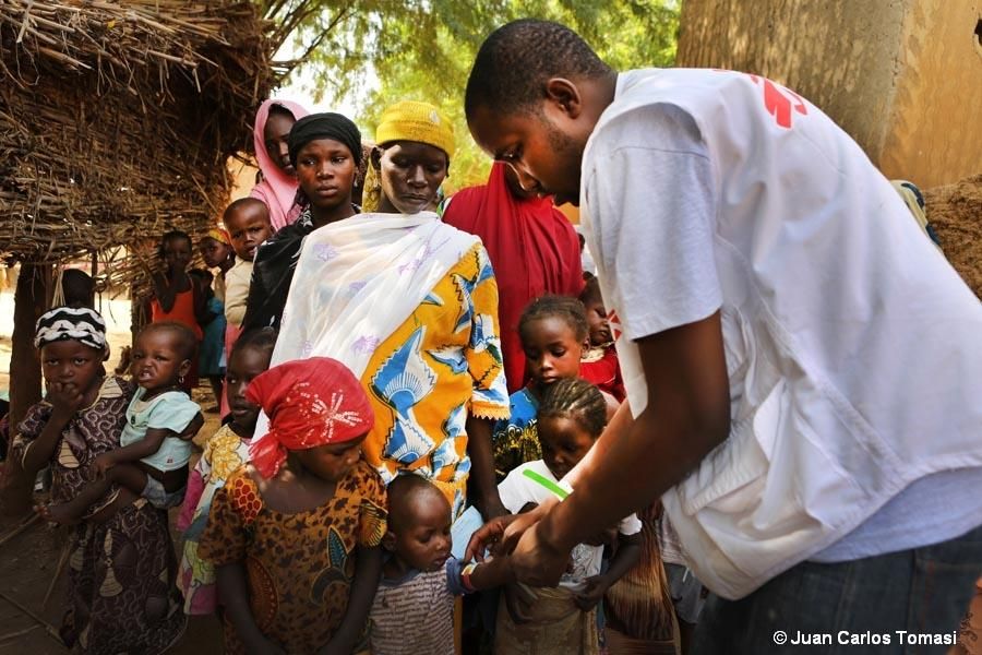 Los agentes comunitarios trabajan para lograr que el máximo número de niños sean atendidos en los puntos donde los equipos de MSF están proporcionando quimioprevención de la malaria. Las autoridades locales también participan en esta tarea de sensibilización, animando a las madres a acercarse con sus hijos. En primer lugar se revisa el estado nutricional de los niños, gracias al brazalete MUAC (de medición del perímetro mesobraquial), que permite evaluar rápidamente y de forma aproximada el estado nutricional del niño. Desde primeras horas, hay largas colas. Esta es en el pueblo de Tounfafi. / Fotografía: MSF