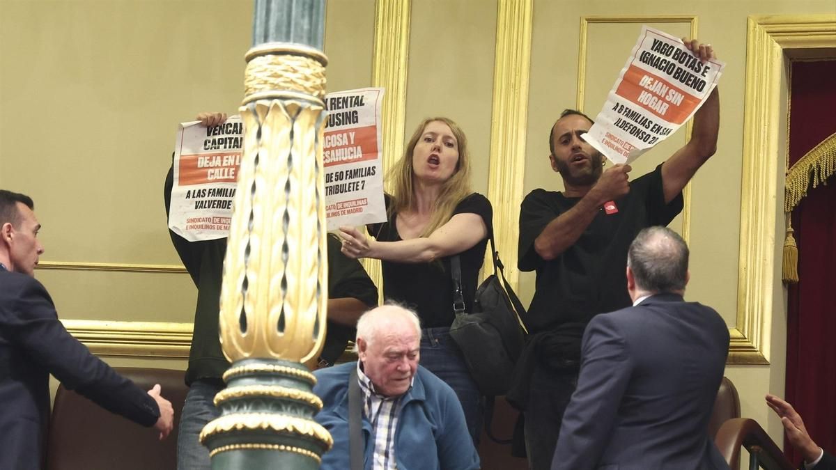 Personas muestran carteles en la tribuna de público del Congreso de los Diputados.