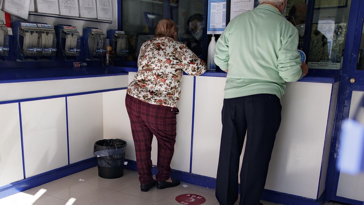 Archivo - Un hombre y una mujer compran lotería en una Administración. Imagen de archivo.