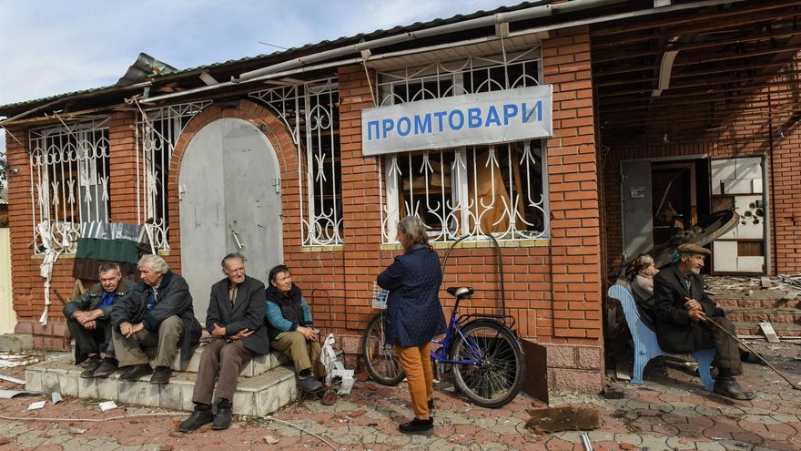 Residentes locales se sientan en los escalones a la salida de una tienda de verduras en la localidad de Yatskivka, en la región de Donetsk.