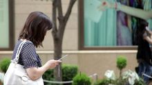 Una mujer mira su teléfono móvil en una calle.
