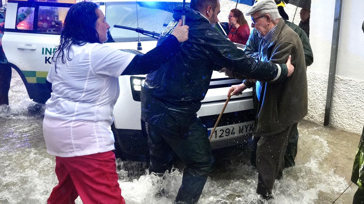 Vecinos de Grazalema ayudan a una persona mayor en una calle inundada debido a las intensas lluvias que se registran este miércoles en la localidad gaditana, que acumula 238,3 litros por metro cuadrado. EFE/Román Ríos.