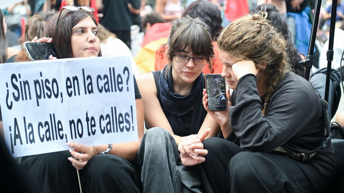 Varias personas escuchan el lunes el anuncio de Sánchez sobre las elecciones
