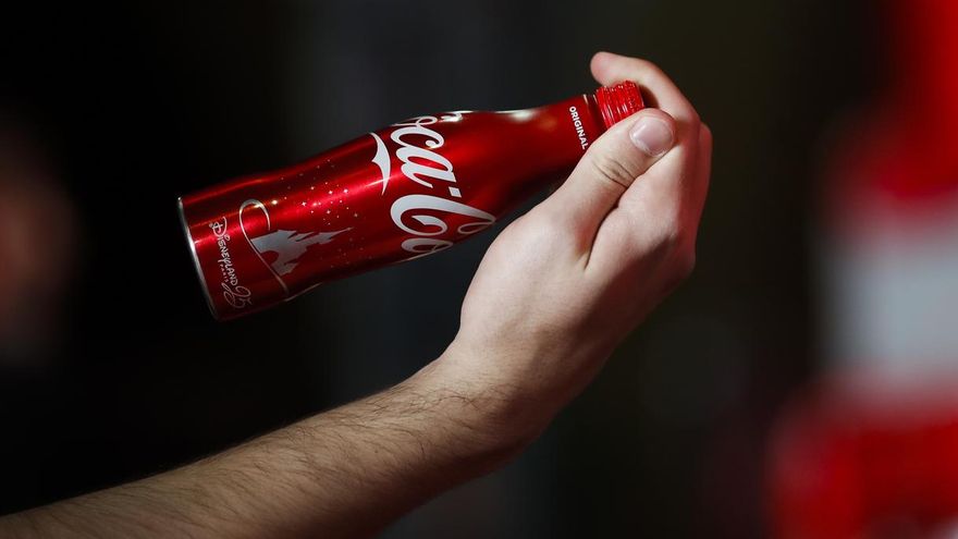 Un hombre sostiene una botella de Coca-Cola.