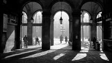 Fotografía del pasaje Madoz, una de las entradas a la plaza Reial de Barcelona, realizada en 1980 por José Antonio Sancho, y que aparece en la portada del libro "Vida i miracles de la plaça Reial", en el que Xavier Theros ha retratado la emblemática plaza Reial de Barcelona, construida a mediados del siglo XIX, que es un oasis dentro de la bulliciosa capital catalana, un rincón apacible que esconde, sin embargo, múltiples secretos, luces y sombras.