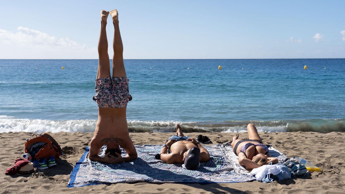 Varias personas, tomando el sol en una playa de Canarias.