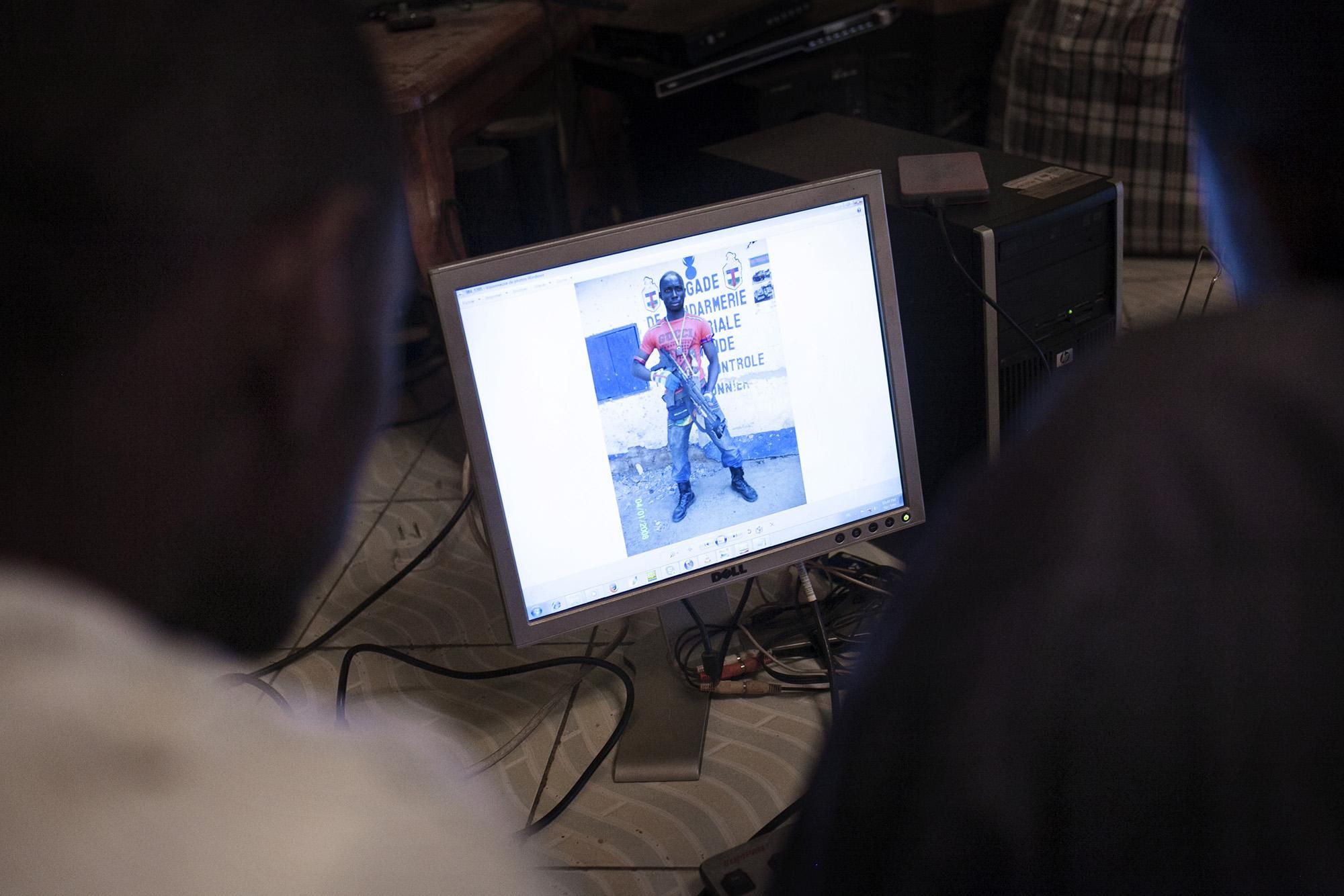 Voluntarios de una asociación local observan las fotografías de los Anti-Balaka apostados en el lado centroafricano de la frontera que se encuentra a pocos centenares de metros de su casa. En los últimos meses los Anti-Balaka se han armado fuertemente, mucho del material militar proviene de antiguos soldados del presidente derrocado François Bozizé que después del golpe de Estado escondieron las armas para recuperarlas ahora./Albert Masias