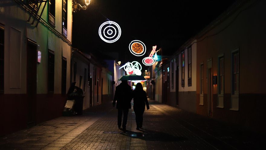 Dos personas pasean bajo el alumbrado navideño por una calle de La Laguna