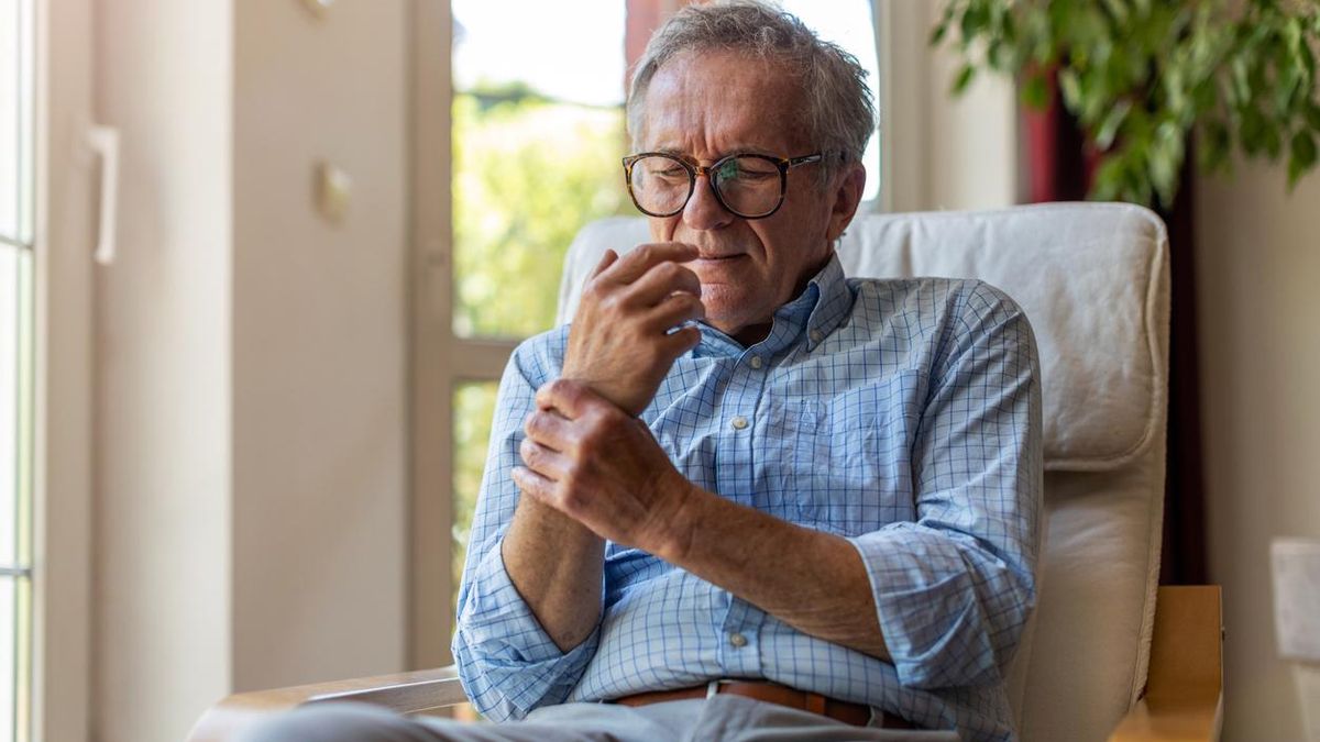 Un hombre se toca la muñeca por el dolor