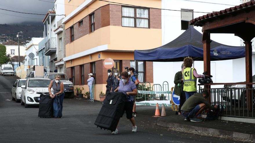 Dos mujeres cargan con sus bienes personales en el camino de Cruz Chica, en el municipio de Los Llanos de Aridane, antes de que la lava sepulte sus casas