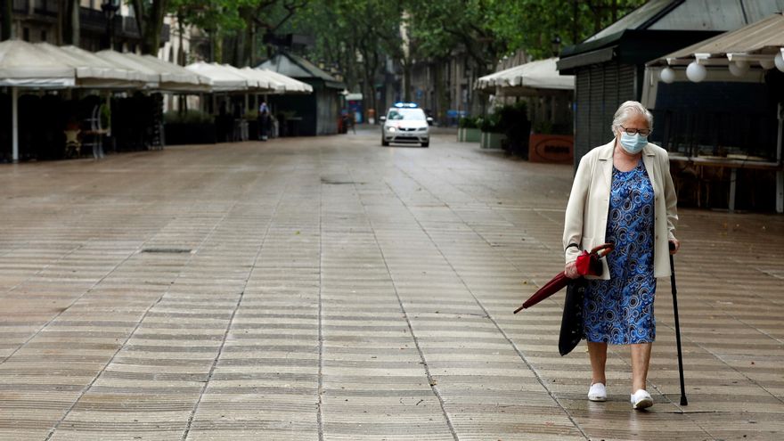 Una anciana protegida con mascarilla pasea por Barcelona.- EFE/Toni Albir/Archivo