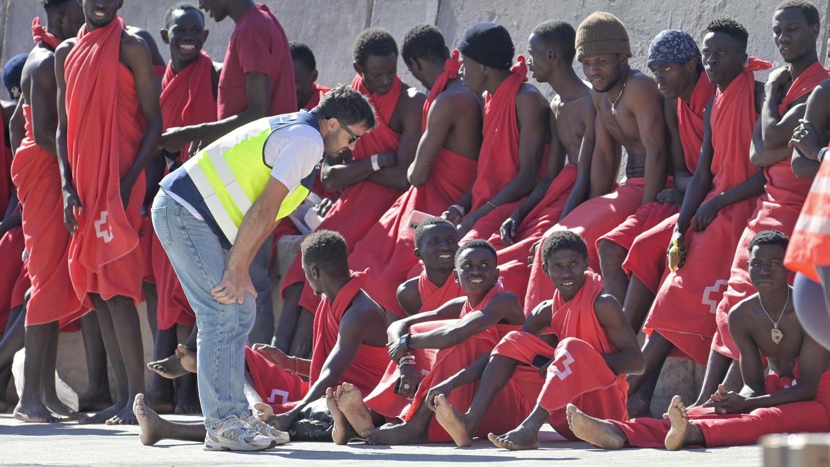 Un agente de la Policía Nacional, con las personas llegadas este martes en cayuco a El Hierro.