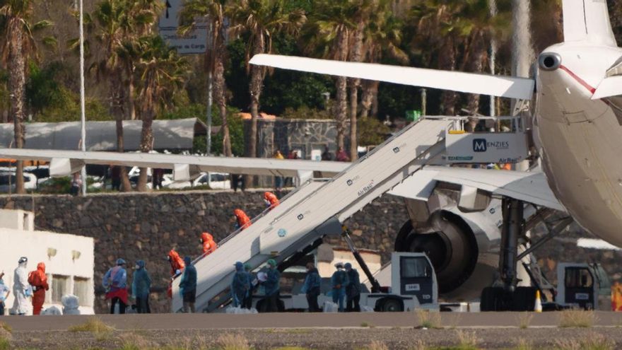 Miembros de la Unidad Militar de Emergencias con trajes de protección en la escalerilla de la aeronave.