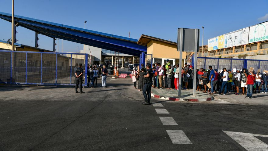 Agentes de Policía supervisan a cientos de personas, la mayoría marroquíes, que guardan cola en la oficina para tramitar los asilos situada en la frontera del Tarajal que separa Ceuta de Marruecos, a 3 de agosto de 2021.
