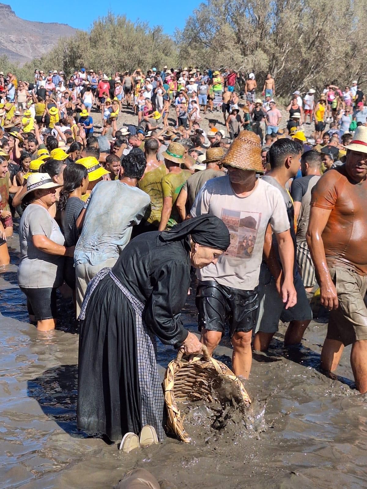 Una mujer de La Aldea atrapa en su cesto algunos peces del charco que da nombre a la popular fiesta grancanaria.