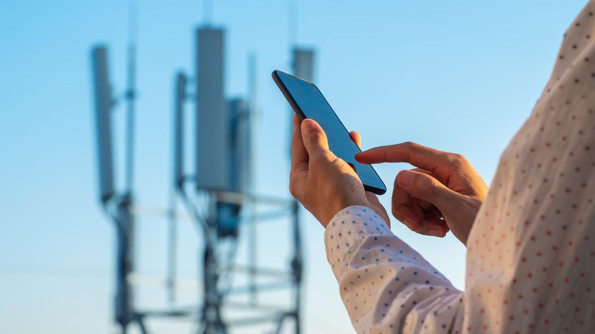 Torre de comunicaciones 5G con hombre usando el teléfono móvil.