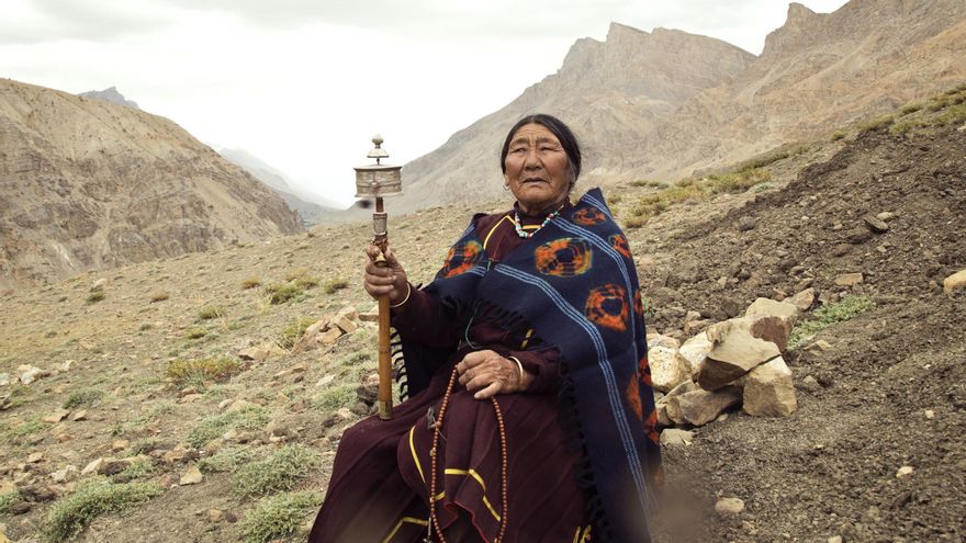 Una mujer con volante de la oración en las montañas del Himalaya.