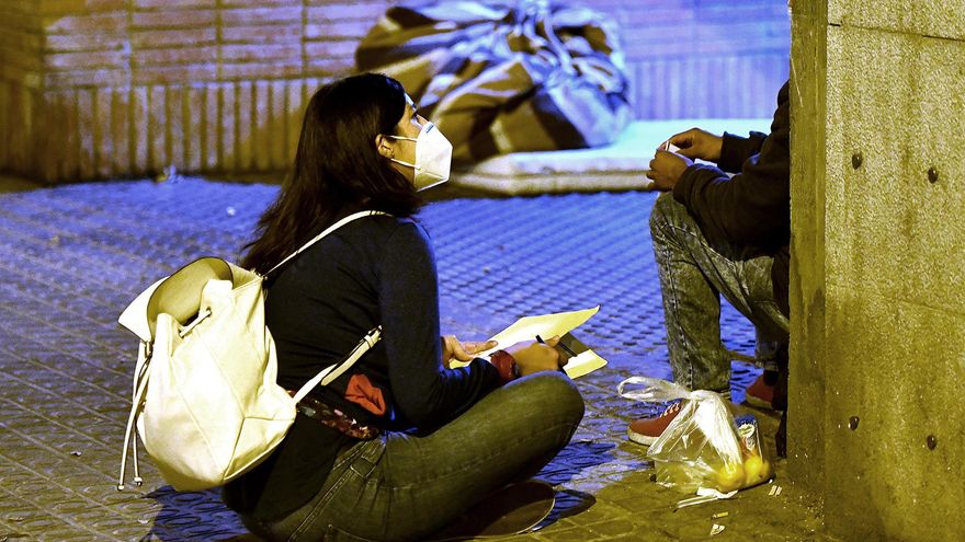 Gisele, voluntaria de la entidad Arrels, informa a una persona sin hogar del toque de queda