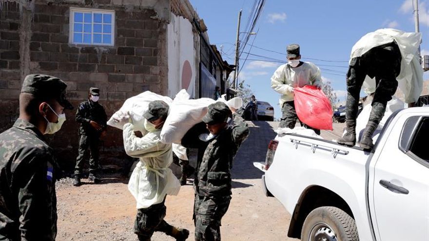 Fotografía cedida este sábado por la Casa Presidencial en la que se registró a militares hondureños al llevar alimentos a personas de escasos recursos de un barrio de Tegucigalpa (Honduras).