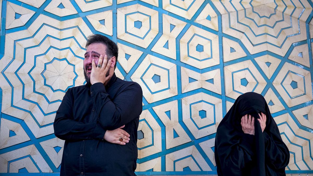 Dos personas lloran en el funeral del asesinado líder supremo de Irán Jamenei en la mezquita Mosala de Teherán.